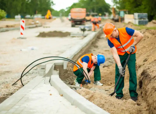 Bauarbeiter verlegen Kabel auf einer Straßenbaustelle.
